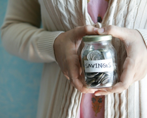 a woman holding a jar with savings written on it